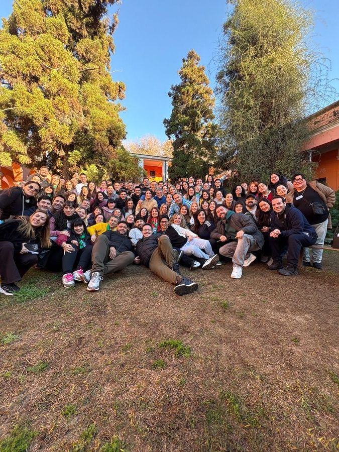Un grupo grande de estudiantes celebra en el jardín de la sede