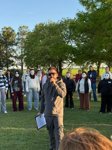 Un facilitador con micrófono guía a participantes con máscaras blancas
