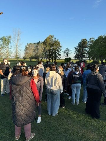 Participantes con máscaras blancas reunidos en el campo durante una dinámica