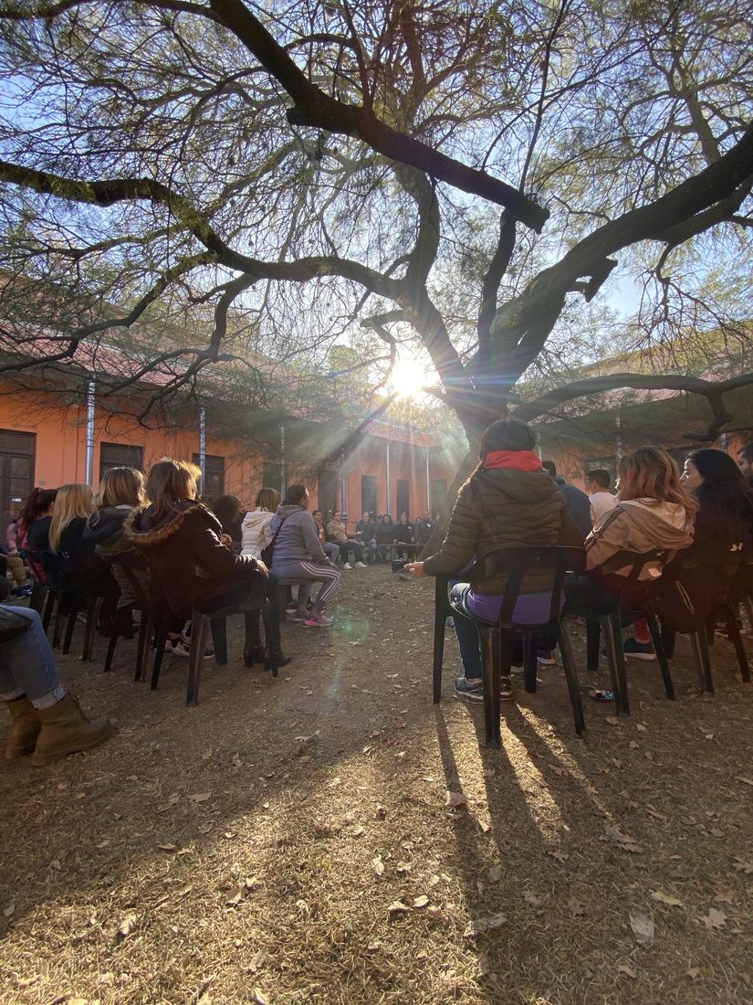 Una ronda bajo un árbol con el sol entre las ramas, en el patio colonial